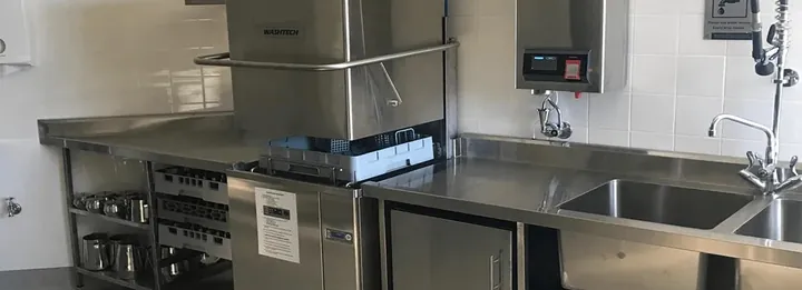 Commercial kitchen with a stainless pass-through dishwasher and sinks