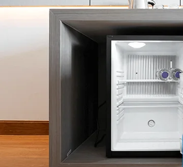 Hotel minibar fridge built into a cabinet with the door open