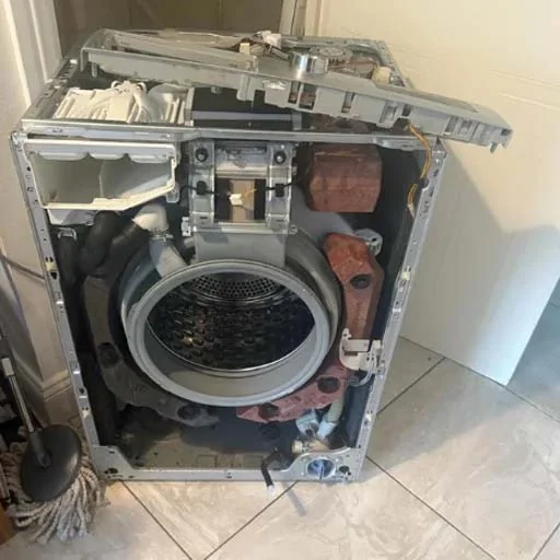 Front-load washing machine stripped down to the drum and counterweights during a repair